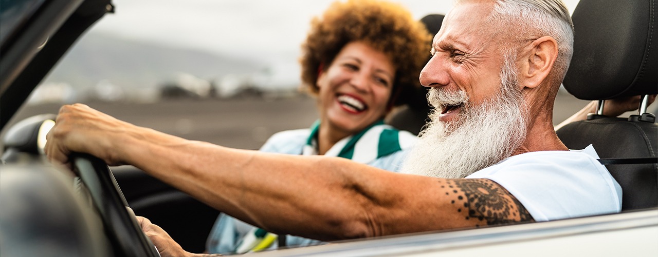 Happy senior couple having fun driving on new convertible car -
